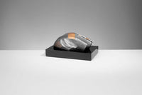 Thumbnail for Eine schlanke, metallische Computermaus mit futuristischem Design präsentiert sich als elegante Trophäe Computer Maus 70 mm x 150 mm PK739678-62593-E25 auf einem schwarzen rechteckigen Ständer vor einem einfachen grauen Hintergrund.
