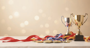 Gold- und Silberpokal mit mehreren Medaillen an Bändern auf einem festlichen Siegertisch – Siegerehrung planen – KI-generiertes Symbolbild
