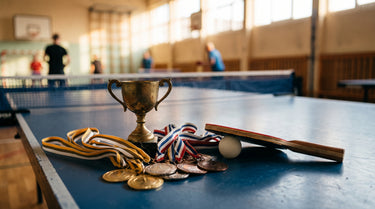Pokal und Medaillen auf einer Tischtennisplatte neben Schläger und Ball – KI-generiertes Symbolbild