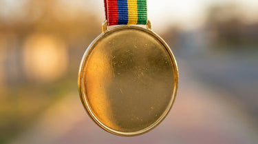 Goldene Sportmedaille mit farbigem Band und glatter Rueckseite fuer die Gravur – KI-generiertes Symbolbild