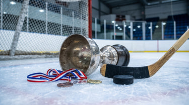 Silberner Pokal und Medaillen auf dem Eis neben Puck und Schläger
