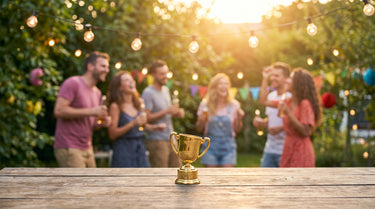 Kleiner goldener Spaßpokal auf einem Tisch bei einer sommerlichen Gartenparty – KI-generiertes Symbolbild