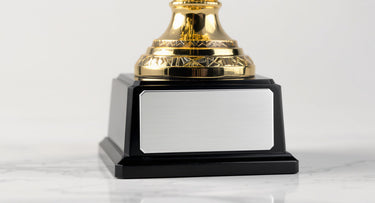 Goldener Pokal mit leerer silberner Gravurplatte auf schwarzem Sockel – Nahaufnahme Pokal-Gravur – KI-generiertes Symbolbild