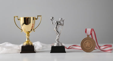 Goldener Pokal, silberne Trophäenfigur und Bronzemedaille am Band nebeneinander – Unterschied zwischen Pokal, Trophäe und Medaille – KI-generiertes Symbolbild