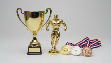 Bodybuilding-Pokal, Kraftsport-Trophäe und Medaillen auf neutralem Hintergrund – KI-generiertes Symbolbild