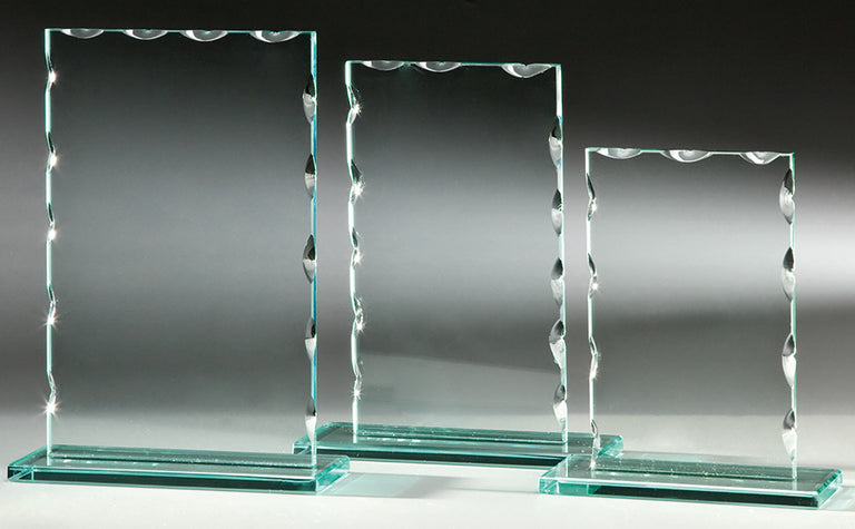 Drei rechteckige Auszeichnungen aus klarem Glas, Awards Karlsruhe 3-er Serie 150x120 mm – 198x150 mm, mit dekorativen, geschwungenen Kanten mit präziser Lasergravur, sind nebeneinander auf einem grauen Hintergrund angeordnet.
