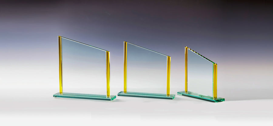 Drei Glaspreise mit gelben Akzenten stehen nebeneinander auf einem Hintergrund mit Farbverlauf, in zunehmender Höhe von links nach rechts. Jeder Preis kann mit Lasergravur personalisiert werden, sodass er sich perfekt für die Präsentation in einer Geschenkbox eignet. Dieses Set wird als Awards Wuppertal 3-er Serie 180x180 mm - 220x225 mm PK767683-81-3 bezeichnet.