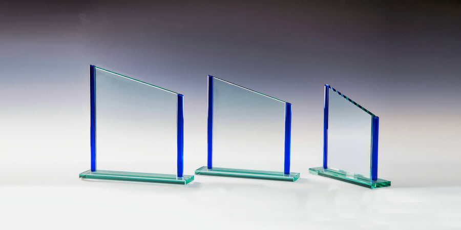 Drei atemberaubende Glasauszeichnungen mit blauen Rändern stehen elegant auf einer weißen Oberfläche vor einem Hintergrund mit Farbverlauf. Jede Auszeichnung Duisburg 3-er Serie 180x180 mm - 220x225 mm PK767686-84-3 variiert leicht in der Größe und zeigt einzigartige Handwerkskunst und Präzision.