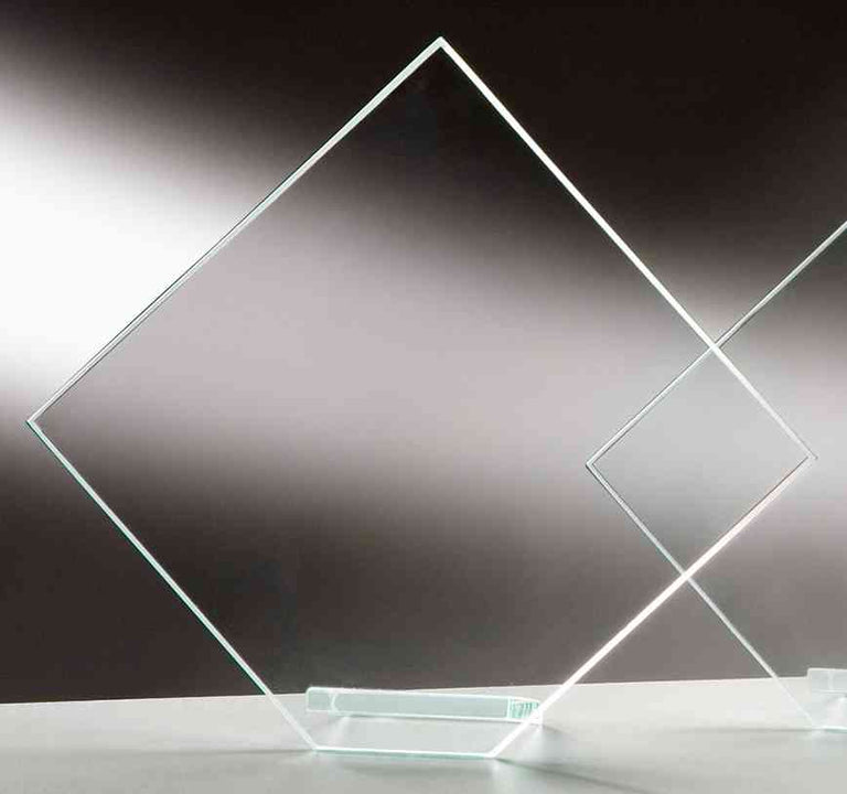 Zwei rautenförmige Klarglasscheiben auf flachem Glassockel, aufrecht vor grauem Hintergrund. Awards Bonn 3-er Serie von POMEKI.