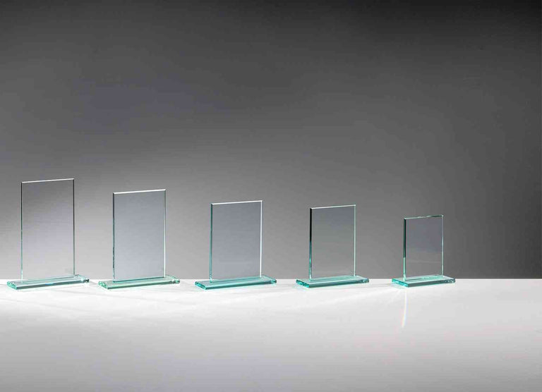 Fünf klare Glasplatten in absteigender Größe auf grünlichen Glassockeln, ohne Gravur, vor grauem Hintergrund. Glaspokal Hamburg 5-er Serie von POMEKI.