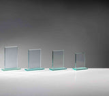 Vier klare Glastafeln in absteigender Größe auf grünlichen Glassockeln, ohne Aufdruck, vor grauem Hintergrund. Glaspokal Köln 4-er Serie von POMEKI.