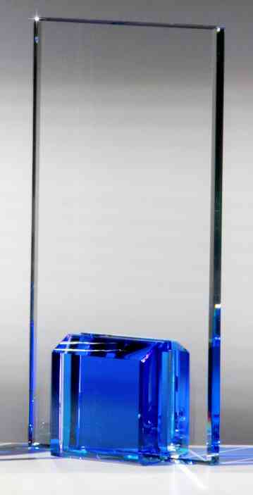 Ein hoher, rechteckiger Glaspokal Dresden 3-er Serie (180 x 100 mm – 220 x 100 mm PK768130-28-3-E50) mit einem kleineren blauen Glaswürfel an der Basis, präsentiert in einer eleganten Geschenkbox.