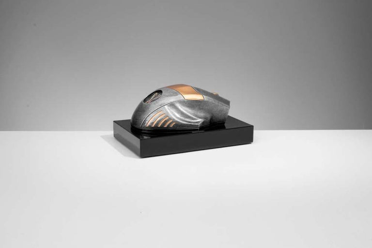 Ein skulpturales Objekt, das einer futuristischen Maus in metallischen Bronze- und Silbertönen ähnelt und auf einem schwarzen rechteckigen Sockel präsentiert wird, ergibt eine elegante Trophäe Computer Maus 70 mm x 150 mm
