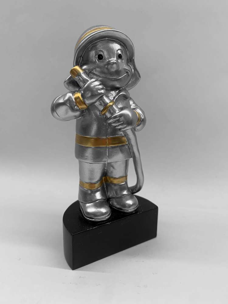 Eine kleine Feuerwehrmannstatue aus Silber und Gold, die einen Schlauch hält und auf einem schwarzen Sockel steht. Diese exquisite Trophäe Kinder Feuerwehr 125 mm dient als perfekte Auszeichnung oder Erinnerungsstück für Tapferkeit und Hingabe.