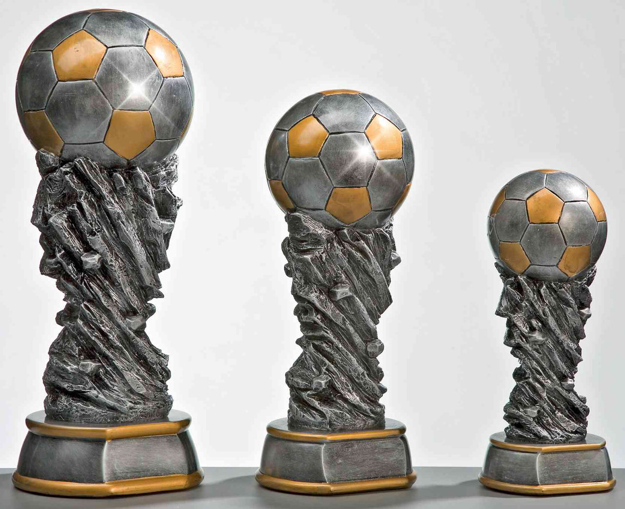 Drei silberne und goldene 3er Serie Fussball 300 mm – 450 mm PK737350-3 in unterschiedlichen Höhen, gefertigt aus hochwertigem Material, zeigen ein exklusives Design vor weißem Hintergrund.