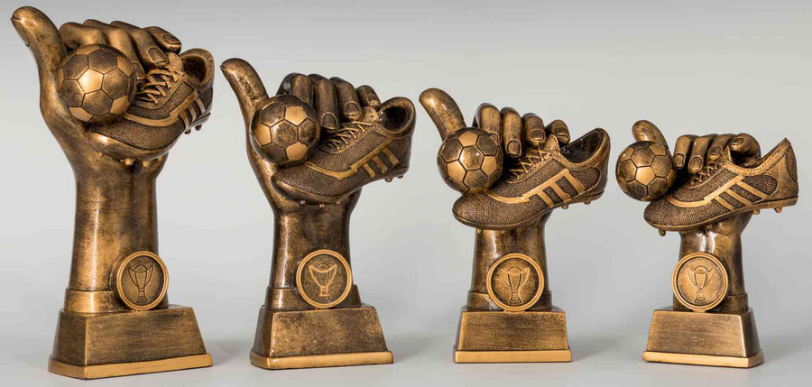 Die 4-er Serie Fußball 130 mm – 202 mm PK739400-4 besteht aus vier bronzenen Fußballtrophäen, die in absteigender Größenreihenfolge von links nach rechts angeordnet sind und jeweils eine Hand zeigen, die einen Fußball und einen Schuh hält.