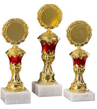 Thumbnail for Drei goldene Pokale Stade 3-er Pokalserie 197 mm – 225 mm PK754650-3-E50 mit roten Akzenten auf weißen Marmorsockeln, nebeneinander ausgestellt.