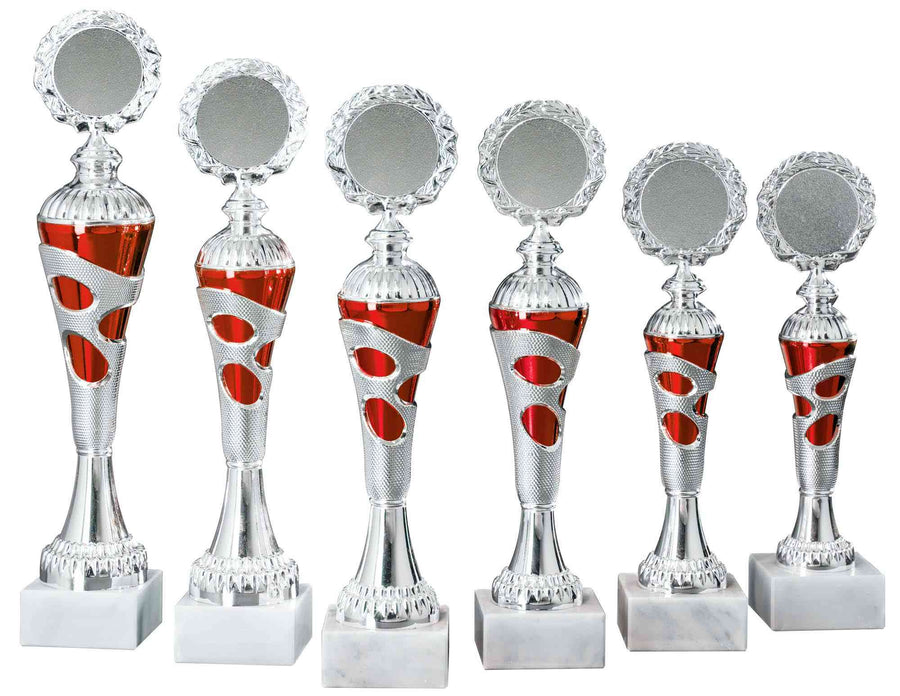 Sechs silberne und rote Pokale Heidenheim 6-er Pokalserie 255 mm – 334 mm PK754730-6-E50 mit runder Oberseite, im exklusiven Design und aus hochwertigem Material gefertigt, stehen auf weißen Marmorsockeln, in zwei Höhenreihen angeordnet.