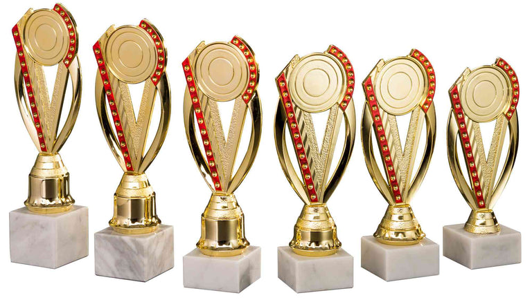 Sechs goldene Trophäen mit roten Akzenten und Marmorsockeln, in einer Reihe angeordnet, dienen als elegante Pokale Baden-Baden 6-er Pokalserie 195 mm - 251 mm für bemerkenswerte Leistungen.