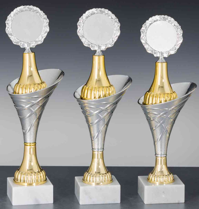 Drei erlesene silberne und goldene 3-er Serie Sonstiges 285 mm – 305 mm mit runden Plaketten auf Marmorsockeln sind in einer Reihe angeordnet.