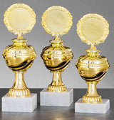 Drei goldene Trophäen, jede mit rundem Emblem und kunstvollem Design, werden auf Marmorsockeln vor neutralem Hintergrund präsentiert. Diese exklusiven Pokale Dessau-Roßlau 3-er Pokalserie 208 mm - 228 mm sind die ideale Auszeichnung für jede prestigeträchtige Veranstaltung.