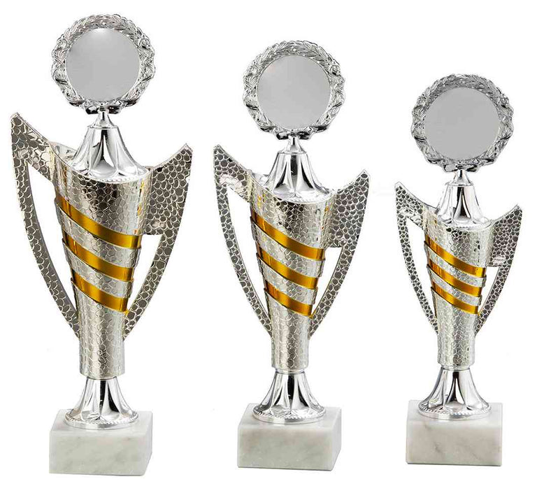 Drei silberne Trophäen unterschiedlicher Höhe mit goldenen Akzenten und Sockeln aus weißem Marmor, aus hochwertigem Material gefertigt und als prestigeträchtige Auszeichnung verliehen, nebeneinander angeordnet: Pokale Detmold 3-er Pokalserie 265 mm - 310 mm
